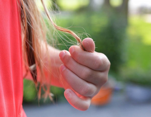 dolgi rjavi lasje deklica z roko drži pramen las zamegljeno ozadje diagnostika clarus